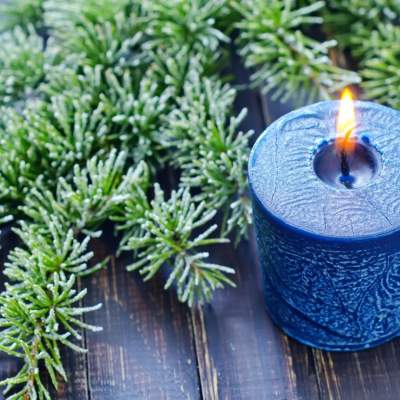 Blue candle on a wooden surface with leaves in the background
